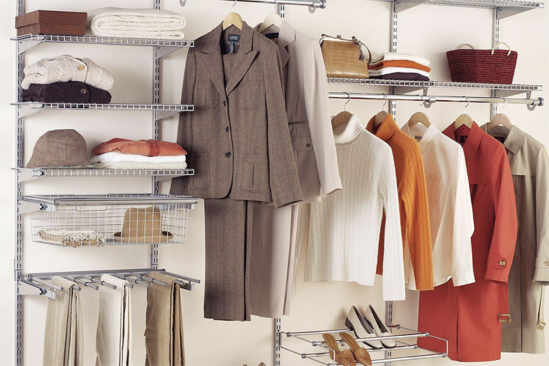 A well-organized closet with several hanging shirts and accessories stacked on white wire organization shelves.