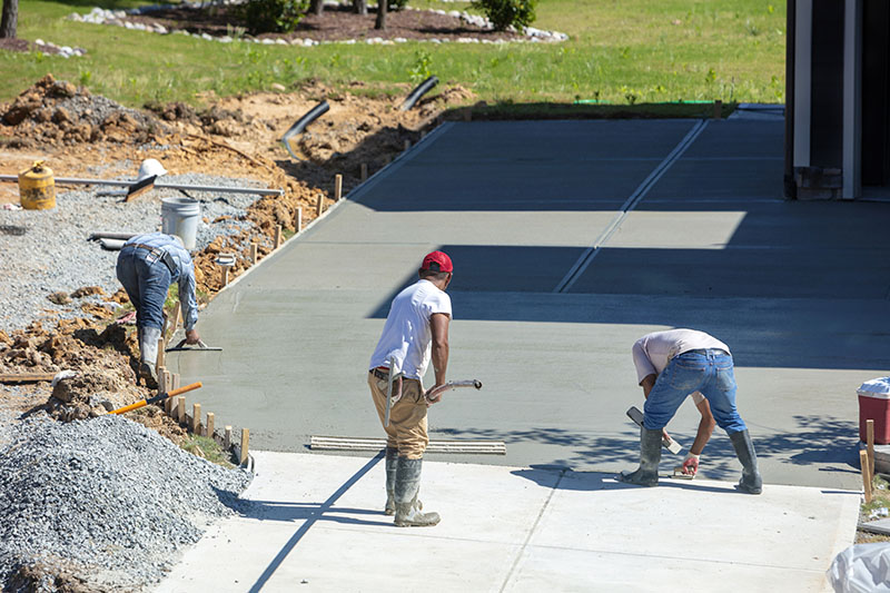 Unidentifiable hispanic men working on a new concrete driveway