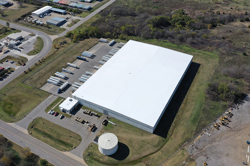 Drone footage of a white metal building from above.