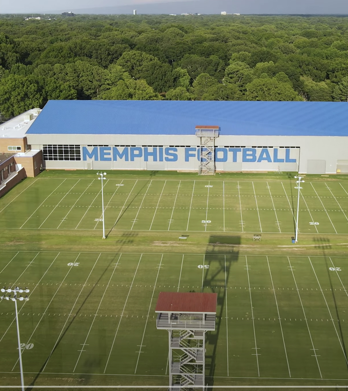 Completed Memphis Football practice facility with blue roof, gray sides, and two practice football fields to the side.